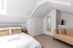 a white bedroom with a bed and a chair at Luxe Design - Boutique Apartment - Heart of Rothbury in Rothbury