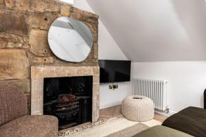 a living room with a stone fireplace and a mirror at Luxe Design - Boutique Apartment - Heart of Rothbury in Rothbury