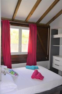 una camera da letto con un letto bianco con tende rosse di Maison Ste Anne/Marin Piscine personnelle vue sur mer a Le Marin