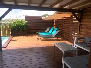 una terraza de madera con 2 sillas y una sombrilla en Maison Ste Anne/Marin Piscine personnelle vue sur mer, en Le Marin