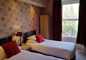 um quarto de hotel com duas camas e uma janela em Albany House em Penrith