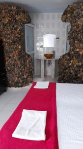 um quarto com um tapete vermelho e uma cama com duas toalhas brancas em Eco-Hotel Villa Elina em Ríohacha