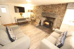 a living room with a couch and a stone fireplace at Zen Cottage Seatown Cullen in Cullen