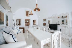 a white dining room with a white table and chairs at Astrea Suites "Ostria Cave Villa-outdoor Jacuzzi" in Oia