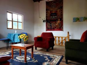 una sala de estar con sillas y una mesa con un jarrón de flores en Hosteria Rose Cottage en Otavalo