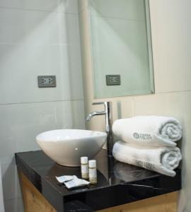 uma casa de banho com lavatório, espelho e toalhas em Hotel Tierra del Sol Moquegua em Moquegua
