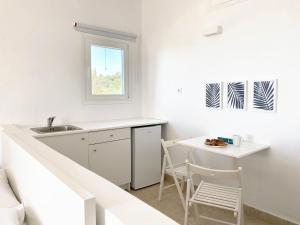 cocina blanca con fregadero y mesa en Palm Suite Blue en Porto Heli