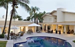 uma casa com piscina em frente a uma casa em Maison Neoclássica 5 estrelas confort em Ribeirão Preto