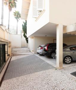 a building with two cars parked in a parking lot at Maison Neoclássica 5 estrelas confort in Ribeirão Preto