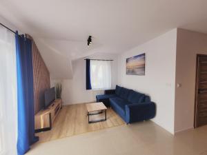 a living room with a blue couch and a table at Apartamenty Morski Brzeg - Sauna, Balia in Władysławowo