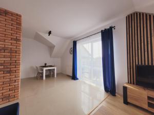 a living room with a large window with blue curtains at Apartamenty Morski Brzeg - Sauna, Balia in Władysławowo