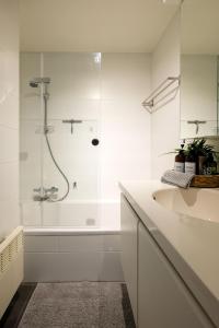 baño blanco con ducha y lavamanos en Location Commodore Oostende, en Ostende