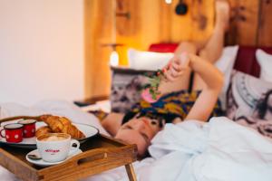 a person laying in bed with a tray of food at PEST-BUDA Design Hotel in Budapest