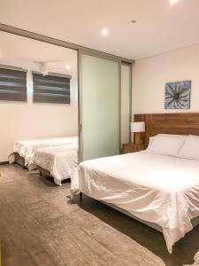 Gz Tower Apartamento Barranquilla في بارانكويلا: سريرين في غرفة نوم مع ملاءات بيضاء
