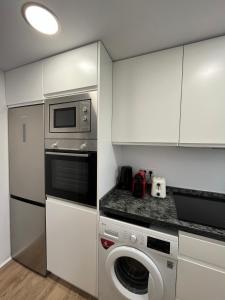 a kitchen with a washing machine and a microwave at Requena12 in Villajoyosa +3 photos