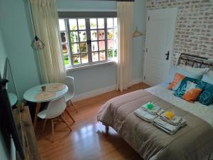 a bedroom with a bed and a table and a window at Casa Verde - Suíte 2 - Iúcas, Teresópolis, RJ in Teresópolis