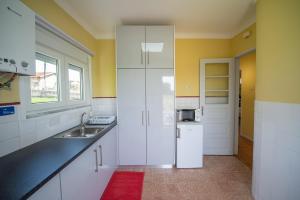 a white kitchen with a sink and a refrigerator at Casa do Carvalhal - natureza no centro da cidade in Santa Maria Da Feira