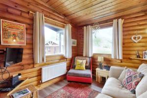 a living room with a couch and a tv and windows at Harbottle Lodge in Longframlington