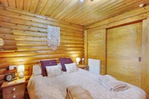 a bedroom with a bed in a log cabin at Harbottle Lodge in Longframlington