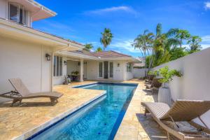 a villa with a swimming pool and a house at Aloha 'Ohana home in Koloa
