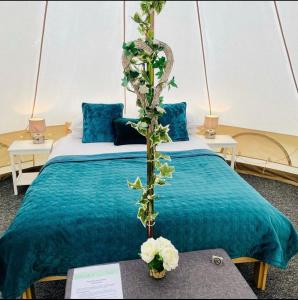 a room with a bed with blue sheets and flowers at Oxford Riverside Glamping in Oxford