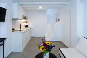a white kitchen with a vase of flowers on a table at Skepi Town Houses in Mikonos