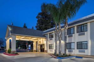 a hotel with a palm tree in front of a building at Best Western Town & Country Lodge in Tulare