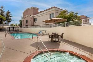 un patio con bañera de hidromasaje y una mesa con sombrilla en Best Western Town & Country Lodge, en Tulare