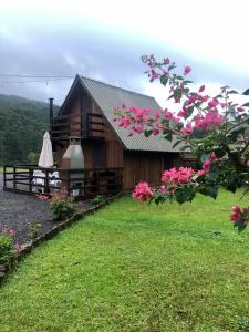a cabin with pink flowers in front of it at Pousada e sítio do Robinho in Timbe do Sul