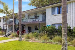 an apartment building with a balcony and palm trees at Seaside Holiday Resort in Fingal Bay