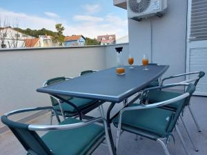 a table and chairs on a balcony with drinks on it at Apartman Stella Marina in Šibenik