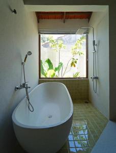 a white bath tub in a bathroom with a window at Nhà mình homestay in Mỹ Lại (1)