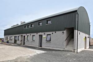 a building with a green roof and a parking lot at Aunt Rachel's Barn Hostel in Bushmills