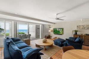 a living room with blue couches and a table at La Mer Apartments in Noosa Heads