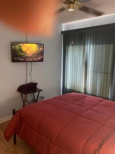 1 dormitorio con cama roja y TV de pantalla plana en Irises House - private room in home, en Kissimmee