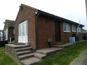 a brick house with stairs leading to a door at Shirls chalet in Sheppey, Leysdown in Leysdown-on-Sea