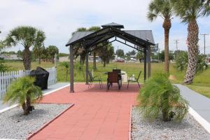 un pabellón con mesa, sillas y palmeras en Travel Inn Fort Pierce, en Fort Pierce