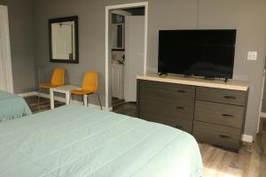 Un dormitorio con una cama y un televisor sobre una cómoda. en Travel Inn Fort Pierce, en Fort Pierce