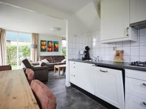 uma cozinha com armários brancos e uma sala de estar em Cozy holiday home with wellness located in Zeeland em heinkenszand