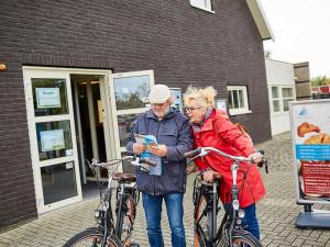 a man and a woman standing next to bikes at Holiday Home in Zeeland with Garden in Heinkensand