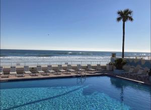 a swimming pool with chairs and the beach at Fountain Beach Resort Studios in Daytona Beach