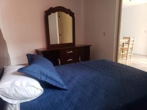 1 dormitorio con cama azul y espejo en Posada MemeLulu en Nanacamilpa