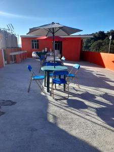 una mesa y sillas con una sombrilla en el patio en Posada MemeLulu en Nanacamilpa