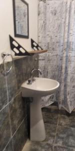 a bathroom with a white sink and a shower curtain at Casita de la montaña in Río Ceballos