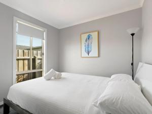 ein weißes Schlafzimmer mit einem Bett und einem Fenster in der Unterkunft The Beaches on Lakes Cottage in Lakes Entrance