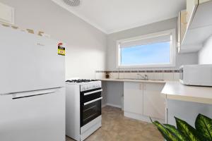 eine Küche mit weißen Geräten und einem Fenster in der Unterkunft The Beaches on Lakes Cottage in Lakes Entrance