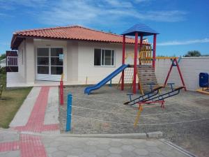 um parque infantil com escorrega em frente a uma casa em Apartamentos com Vista pro Mar de Imbituba residencial mar azul em Imbituba