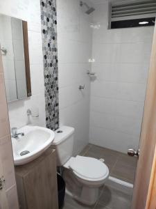 Baño blanco con aseo y lavamanos en APARTAMENTO VACACIONAL MELGAR, en Melgar