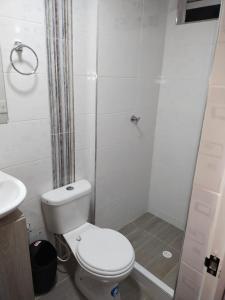 La salle de bains blanche est pourvue d'une douche et de toilettes. dans l'établissement APARTAMENTO VACACIONAL MELGAR, à Melgar