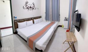 a large bed in a room with a television at Sun Good Hostel in Hengchun South Gate